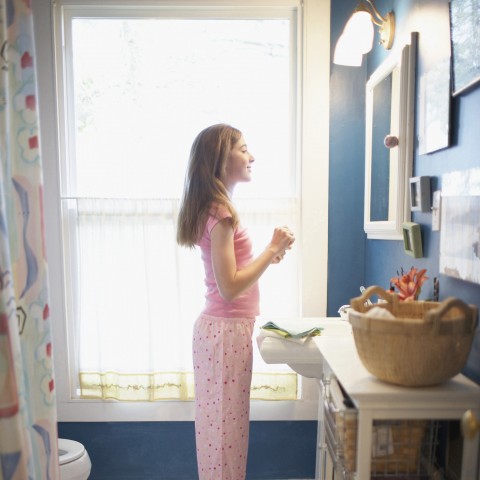 A Woman Standing in Front of a Bathroom Mirror in Her Pajamas