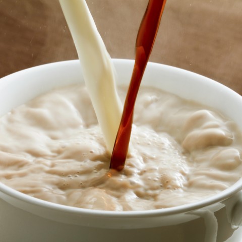 Someone Pouring Coffee and Milk into a Mug