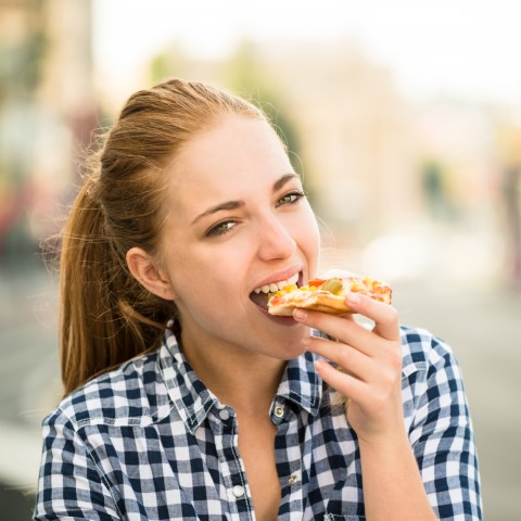 A Woman Eating a Slice of Pizza