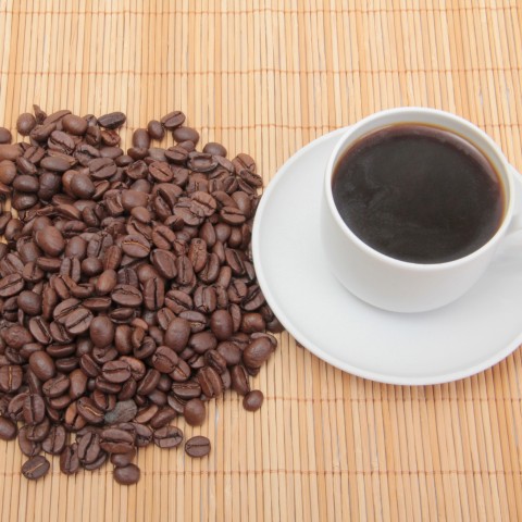 A Pile of Coffee Beans Next to a Cup of Coffee