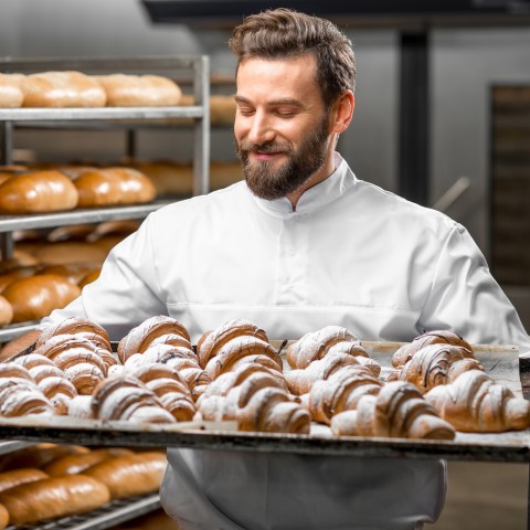 A Baker Holding a Large Tray of Croissants