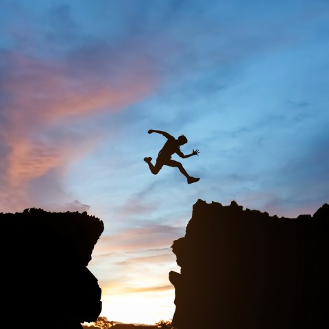 A Silhouette of Someone Leaping from One Cliff to Another