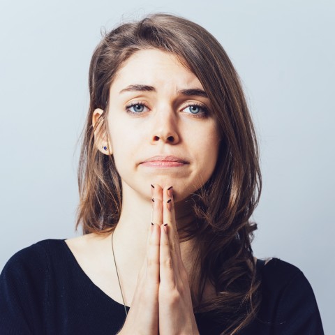 A Woman Asking for Forgiveness with Her Palms Together in Front of Her