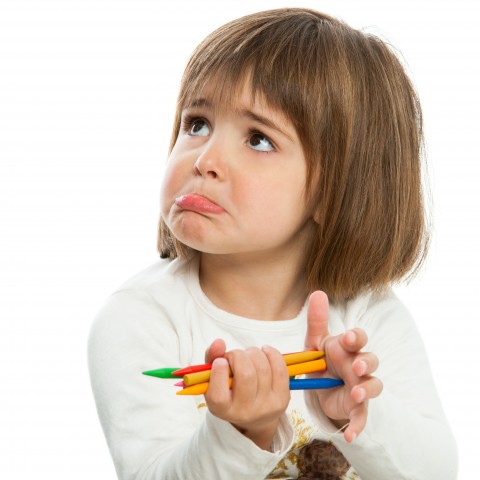 A Little Kid Holding Pencils and Pouting
