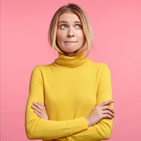 A Woman in a Yellow Long-sleeved Shirt Looking Unsure about Something