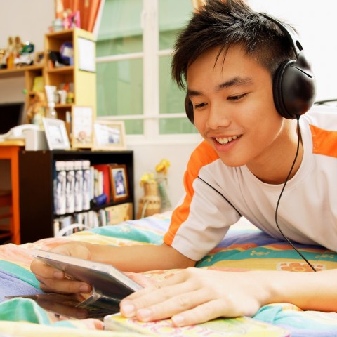 A Young Man in His Bedroom Listening to Podcasts