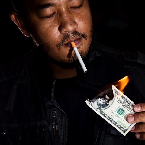 Man Lighting Cigarette with Burning Money