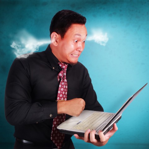 An Angry Man Holding His Laptop, with Smoke Coming Out of His Ears.