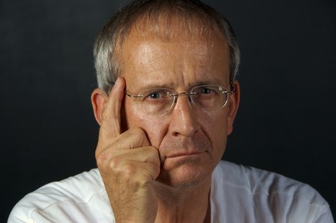 An Older Man Pointing to His Head with an Index Finger