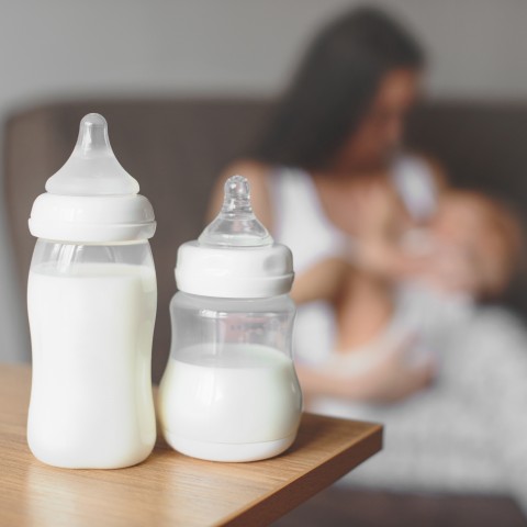 Pair of Baby Bottles with Mother and Child in Background