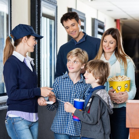 A Family Showing Their Tickets to a Lady at the Movie Theater Ticket Booth