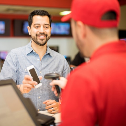 A Staff Member Scanning a Barcode from a Man’s Phone Screen