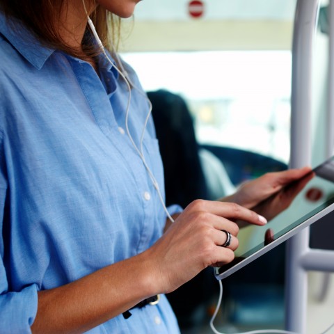The Neck and Torso of a Woman Tapping on a Tablet or iPad Screen.