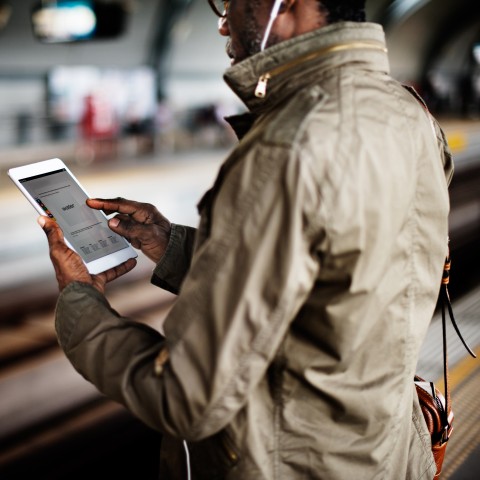 A Man at the Subway Station Reviewing Vocabulary on His Tablet