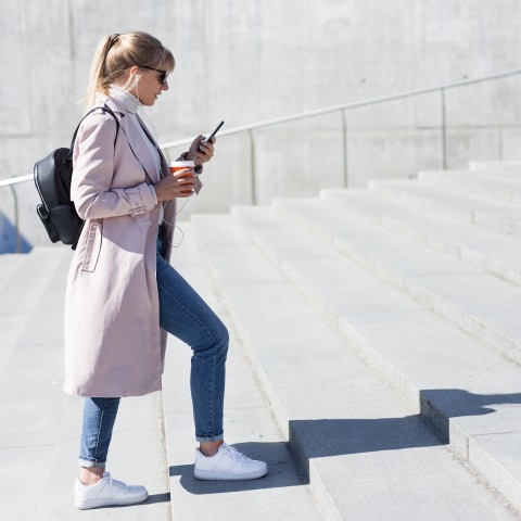 A Woman Walking Up Steps and Listening to Something on Her Phone