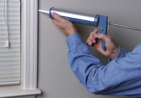 Worker applying sealant around a window