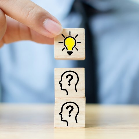 A Man Stacking Cubes, with the Top Cube Having a Lightbulb Picture