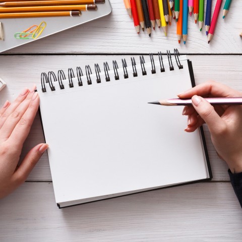 A Blank Notebook with Several Coloured Pencils