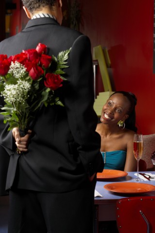 A Man Holding Bouquet of Roses behind His Back for a Woman 