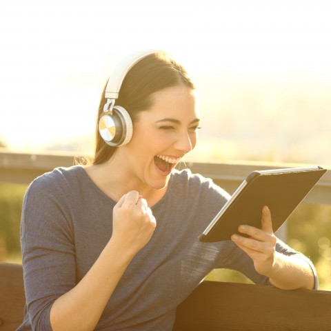 A Happy Woman Celebrating while Listening to Something with Headphones 