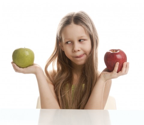 A Girl Choosing between a Green Apple and Red Apple