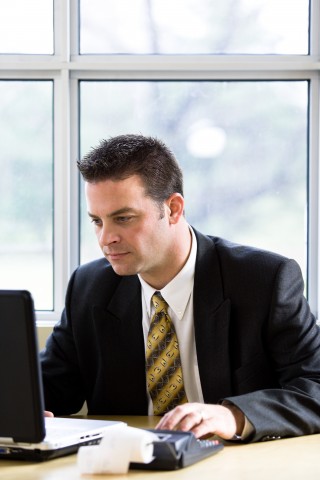 Accountant in Suit Working on Laptop and Calculator