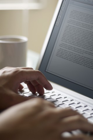 Person typing with coffee next to them