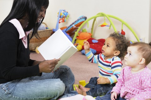 A Woman Reading a Story to Two Toddlers in a Nursery Setting