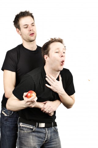 Someone Performing the Heimlich Maneuver on Someone Who Is Choking on an Apple