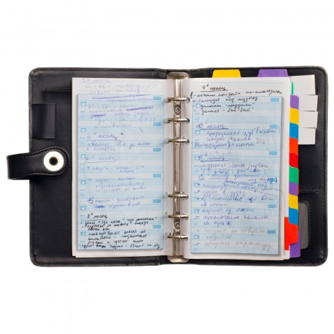 Open weekly planner with handwritten notes and colorful tabs