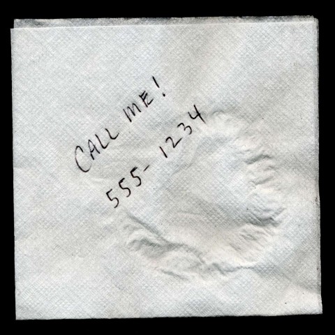 A Napkin that Says Call Me! with a Phone Number Written Down