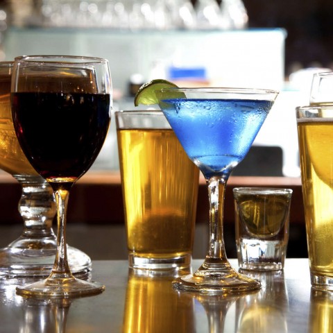 Different alcoholic beverages in glasses on a counter top.