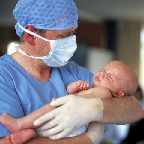 A Newborn Baby being Held by a Doctor