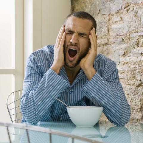 A Man Yawning while Eating Breakfast