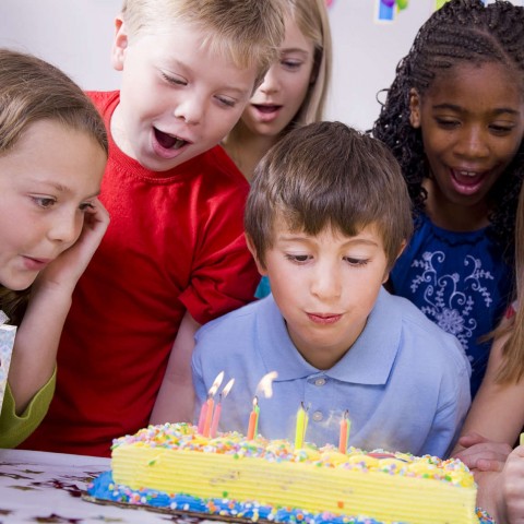 Boy Blowing Out Candles on Birthday Cake