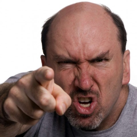 An angry bald man pointing his finger toward his opponent during a heated argument